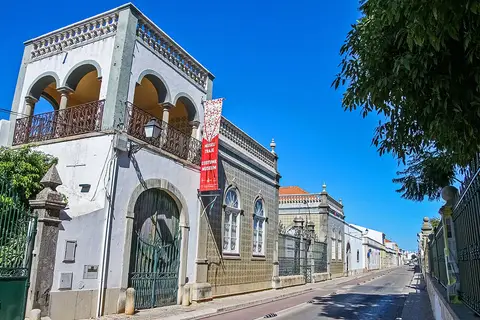 Fachada azulejada do Museu do Traje de São Brás de Alportel, com varanda em arcos e bandeira vermelha