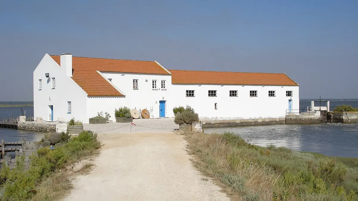Moinho de Maré da Mourisca, edifício branco com telhado vermelho junto ao sapal e ao canal de água