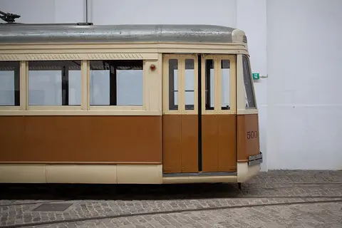 Carro eléctrico histórico número 500, castanho e creme, sobre carris no Museu do Carro Eléctrico