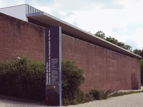 Fachada de tijolo do Planetário do Porto com letreiro vertical à entrada