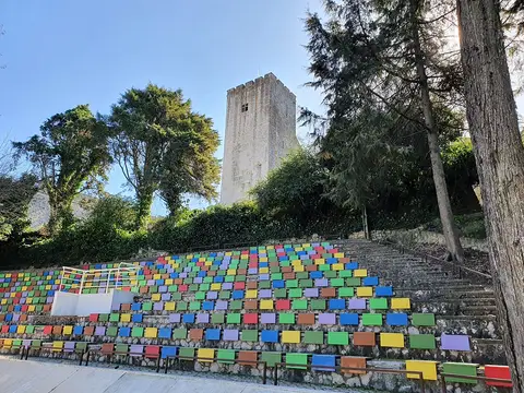 Escadaria com painéis coloridos no Parque Venâncio Ribeiro da Costa, com torre do castelo ao fundo