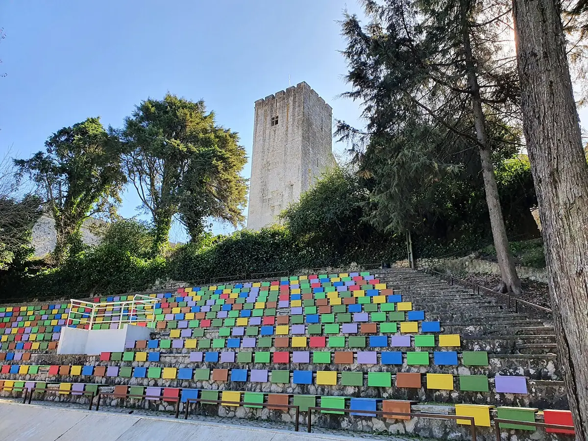 Escadaria com painéis coloridos no Parque Venâncio Ribeiro da Costa, com torre do castelo ao fundo