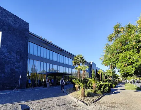 Fachada envidraçada do Hotel Vila Galé em Évora, com palmeiras e jardim à entrada