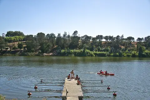 Pontão de madeira sobre o rio no Parque Ecológico do Gameiro, com vegetação na margem oposta