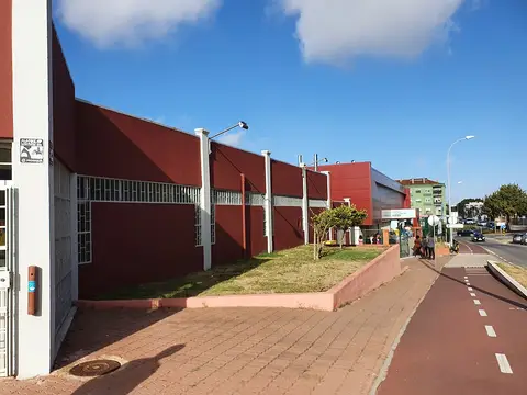 Exterior do edifício vermelho da Piscina Municipal de Ouressa, junto a passeio e ciclovia.