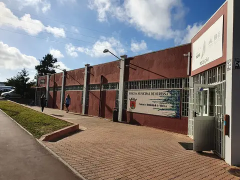 Exterior da Piscina Municipal de Ouressa, edifício vermelho com letreiro e entrada da receção