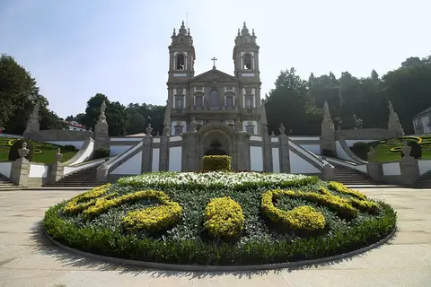 Santuário do Bom Jesus do Monte com canteiro floral em primeiro plano e escadarias laterais