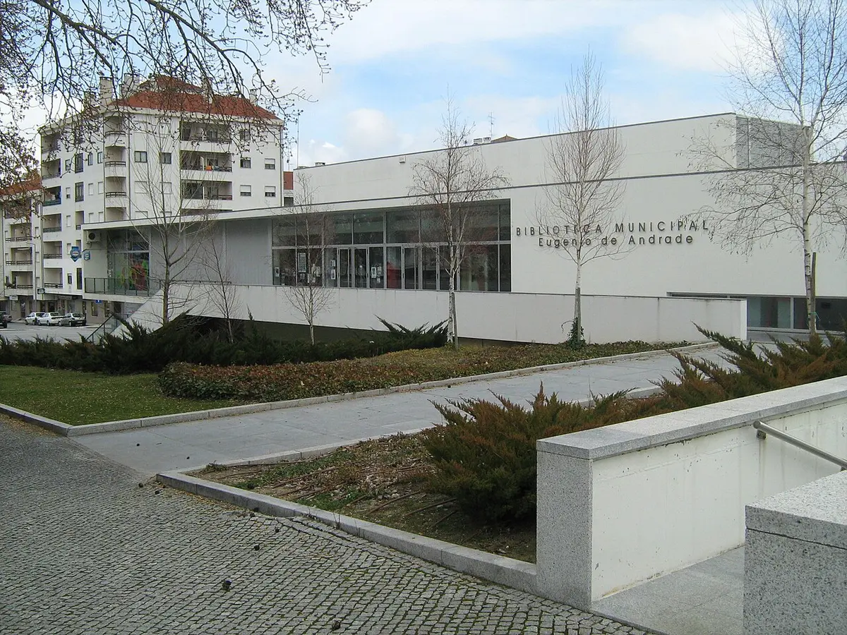 Edifício moderno da Biblioteca Municipal Eugénio de Andrade, com letreiro na fachada branca e jardim em frente