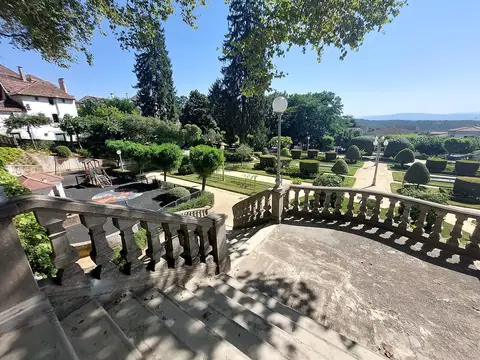 Vista do parque municipal a partir da escadaria com balaustrada, com jardins aparados e parque infantil