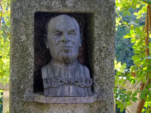 Busto em pedra de Américo Pires de Lima num nicho de granito, rodeado de vegetação, no Jardim Botânico do Porto