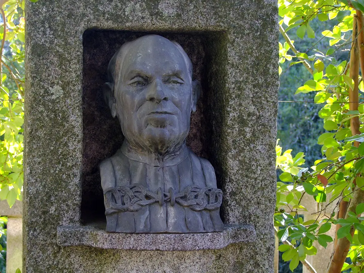 Busto em pedra de Américo Pires de Lima num nicho de granito, rodeado de vegetação, no Jardim Botânico do Porto