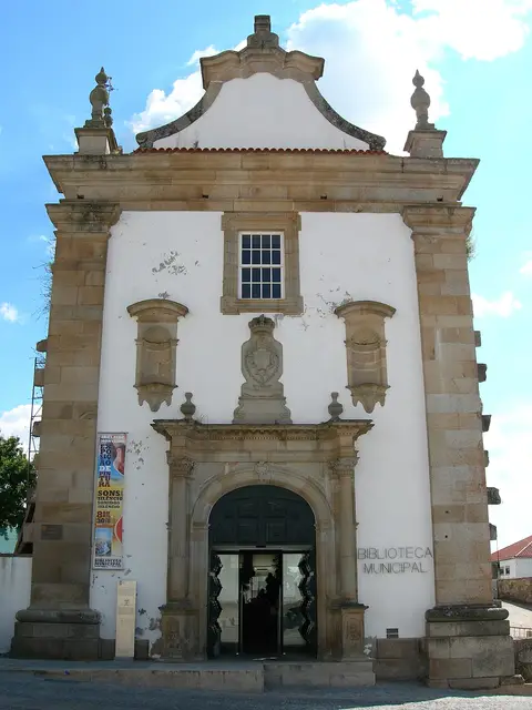 Fachada barroca em pedra e branco da Biblioteca Municipal de Miranda do Douro, com portal em arco.