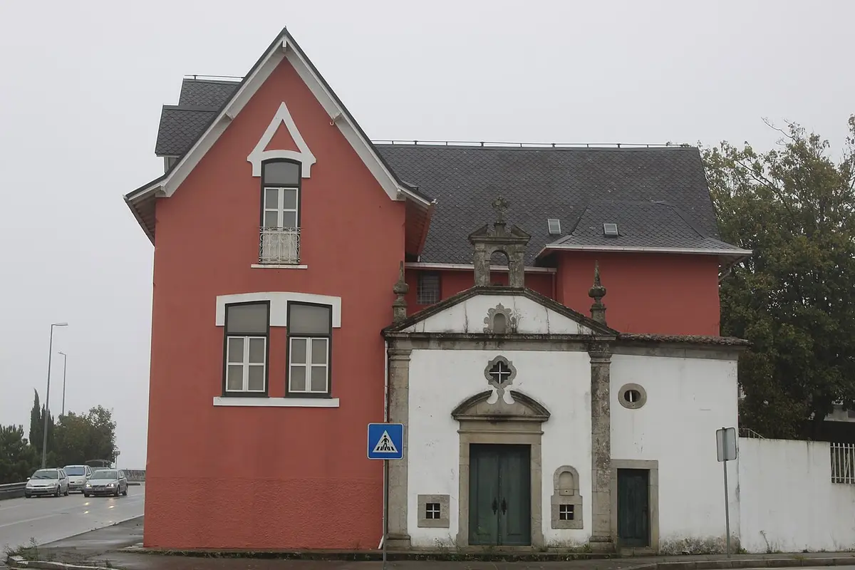 Edifício vermelho da Casa-Museu Abel Salazar junto a uma capela branca com portal em pedra