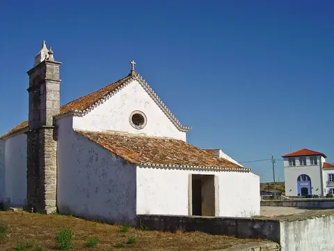 Capela caiada de São Miguel de Odrinhas, com campanário de pedra e telhado de telha, sob céu azul.