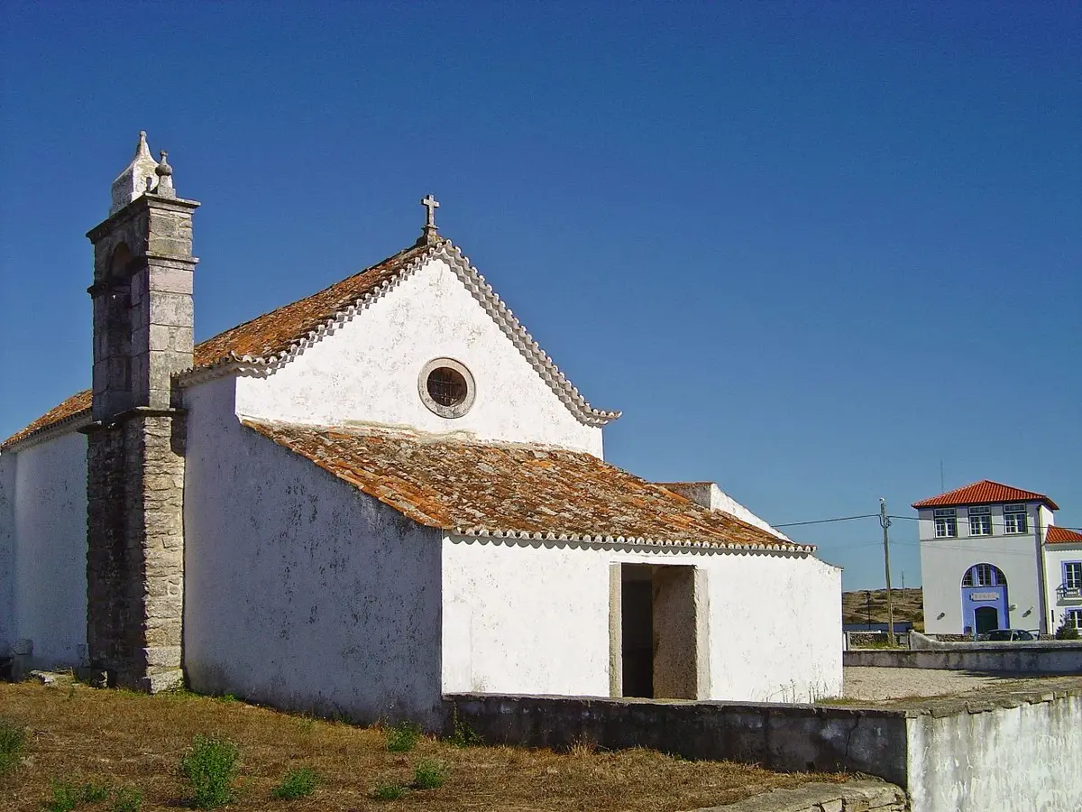 Capela caiada de São Miguel de Odrinhas, com campanário de pedra e telhado de telha, sob céu azul.