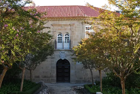 Fachada em granito da Casa do Miradouro, em Viseu, com portal brasonado e jardim com árvores