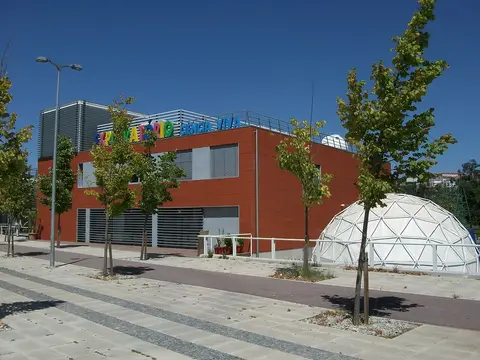 Edifício vermelho do Centro Ciência Viva de Coimbra com cúpula geodésica branca ao lado