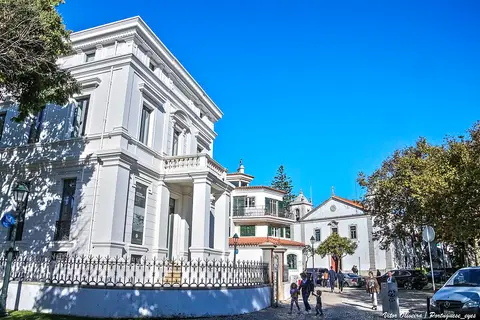 Fachada branca da Casa Sommer em Cascais, com gradeamento de ferro e céu azul