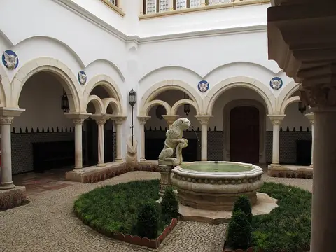 Pátio interior do Museu Condes de Castro Guimarães com arcadas e fonte com leão em pedra