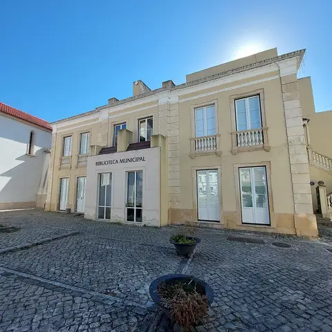 Fachada principal da Biblioteca Municipal de Soure, edifício claro com letreiro, visto do largo calcetado