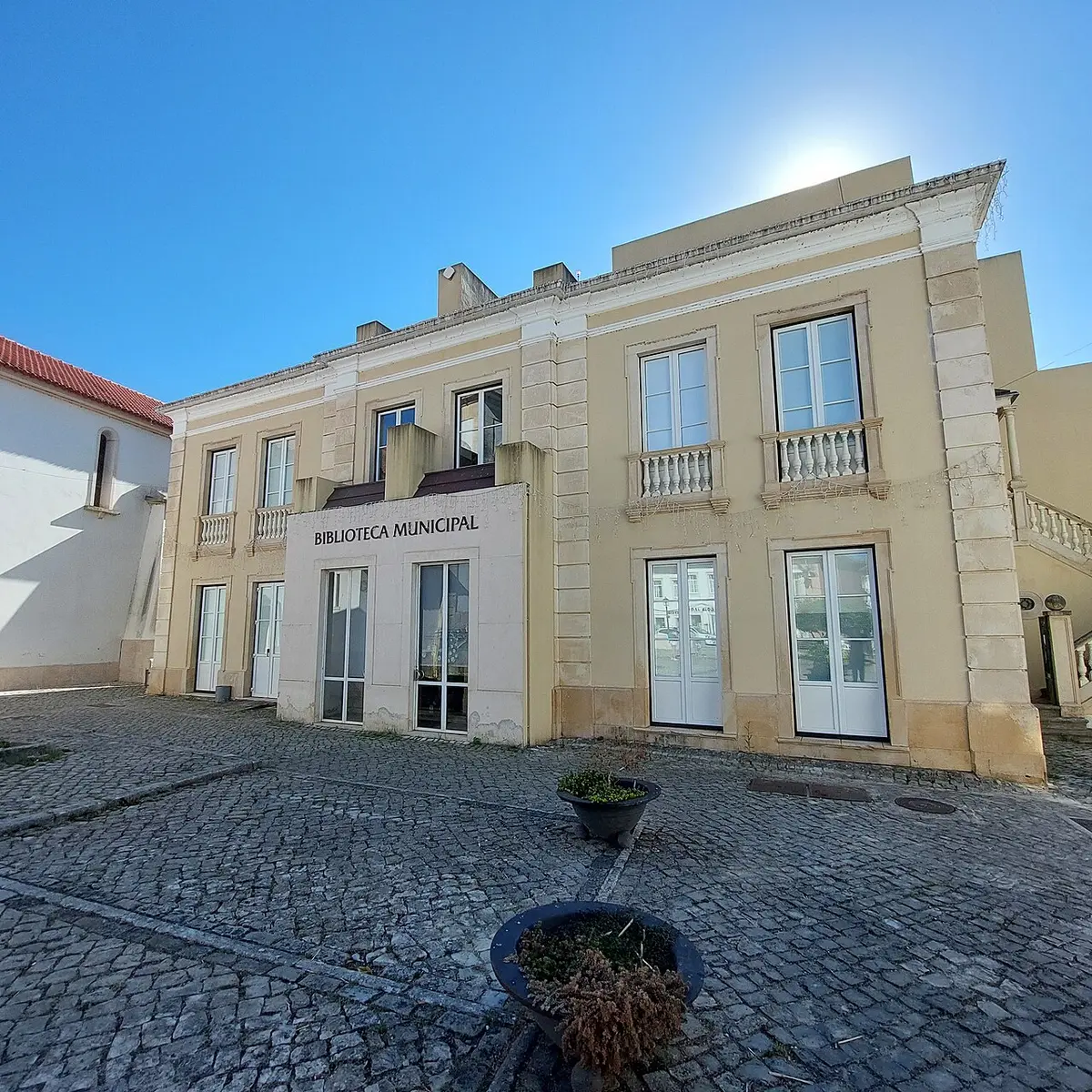 Fachada principal da Biblioteca Municipal de Soure, edifício claro com letreiro, visto do largo calcetado
