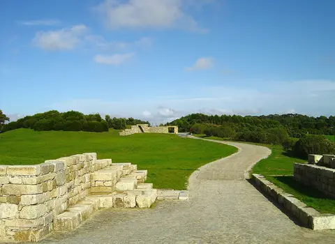 Caminho de terra batida entre muros de pedra e relvados verdes no Parque da Cidade do Porto