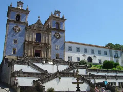 Igreja matriz com fachada azulejada e escadaria, ao lado do edifício branco do Convento dos Lóios