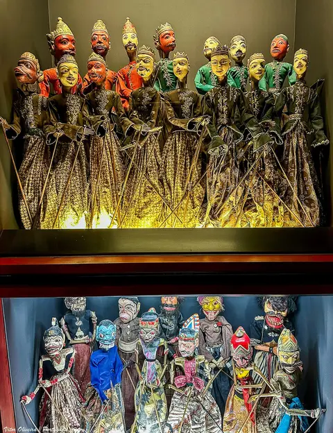 Vitrinas do Museu da Marioneta com marionetas tradicionais coloridas expostas em duas prateleiras iluminadas