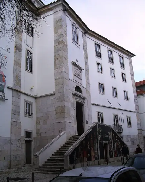 Fachada branca do Museu da Marioneta, em Lisboa, com escadaria de pedra e cartaz à entrada