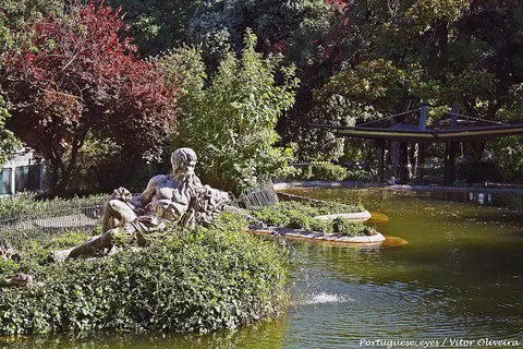 Lago do Jardim da Estrela com estátua reclinada rodeada de vegetação e coreto ao fundo