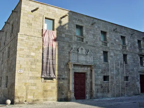 Fachada em pedra do Museu Nacional Grão Vasco, em Viseu, com portal barroco e porta vermelha.