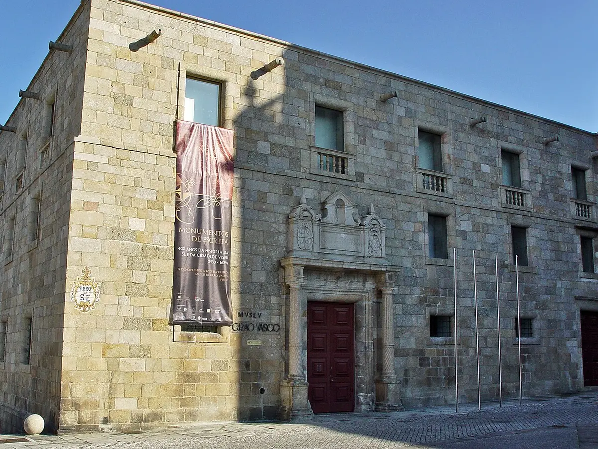 Fachada em pedra do Museu Nacional Grão Vasco, em Viseu, com portal barroco e porta vermelha.