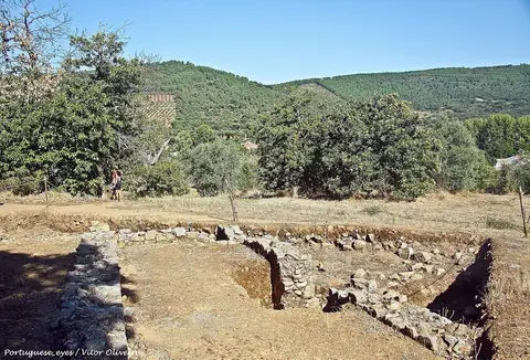 Ruínas de muros de pedra da cidade romana de Ammaia com colinas verdes ao fundo