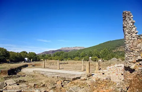 Ruínas da cidade romana de Ammaia com colunas e muros de pedra, serra ao fundo sob céu azul