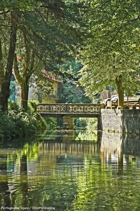 Ponte sobre o rio ladeado de árvores no parque termal do Peso, em Melgaço