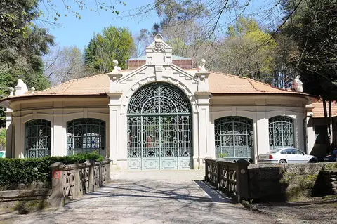 Edifício histórico das termas com portões de ferro forjado, rodeado de árvores