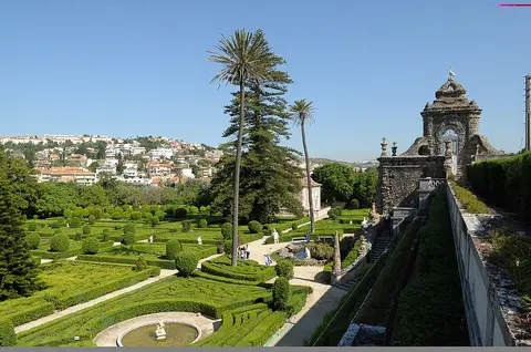 Jardim formal da Quinta Real de Caxias com buxo recortado, palmeiras, lago e cascata em pedra
