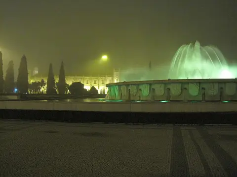 Fonte luminosa da Praça do Império iluminada à noite, com o Mosteiro dos Jerónimos ao fundo