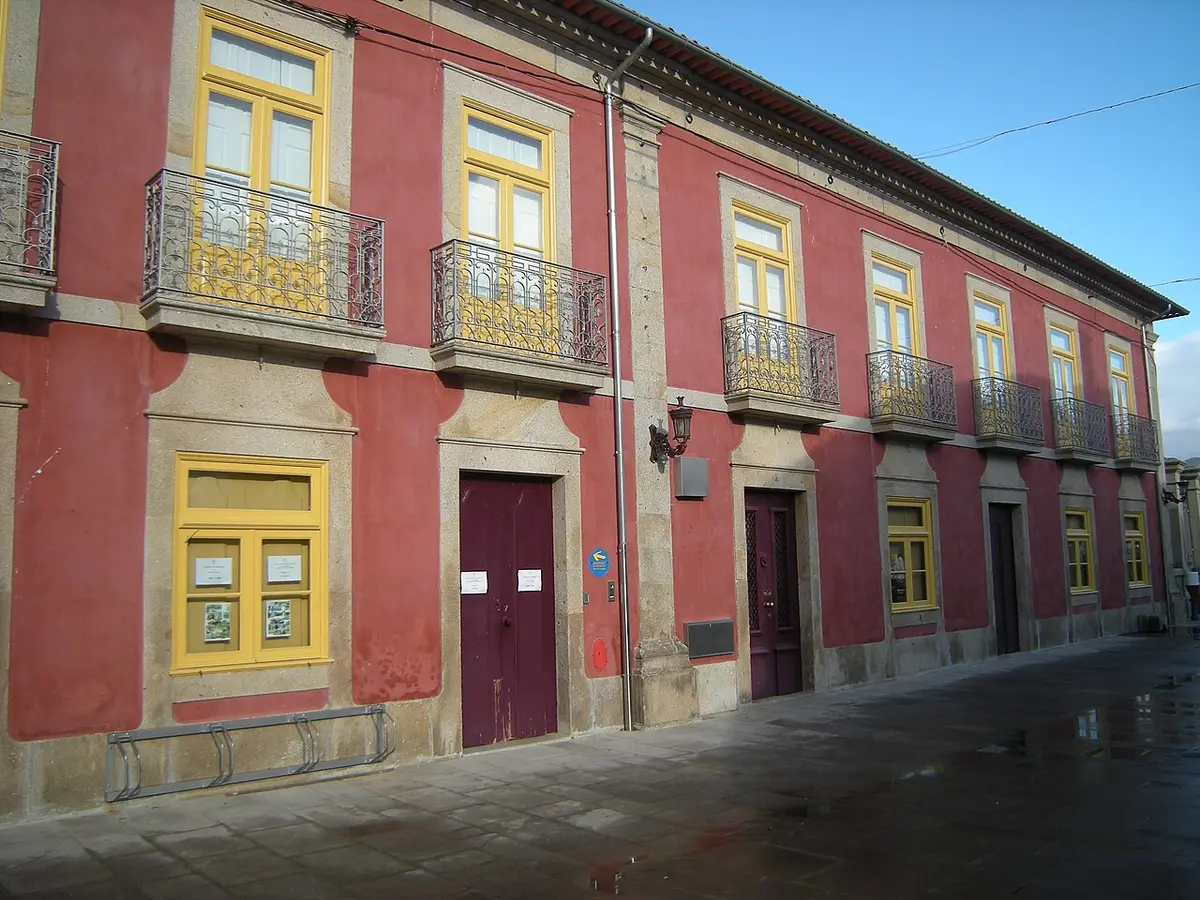 Fachada de edifício histórico rosa com janelas amarelas e varandas de ferro forjado em Ponte de Lima