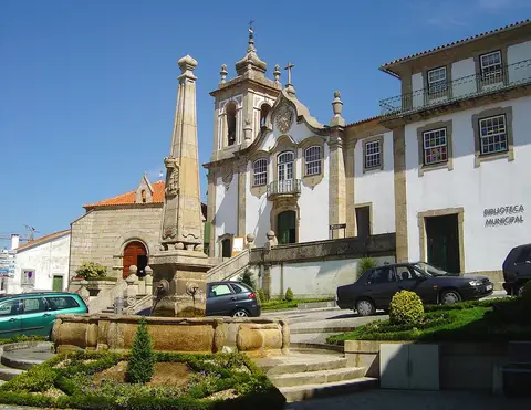 Edifício da Biblioteca Municipal de Seia junto a igreja barroca e chafariz de pedra em praça