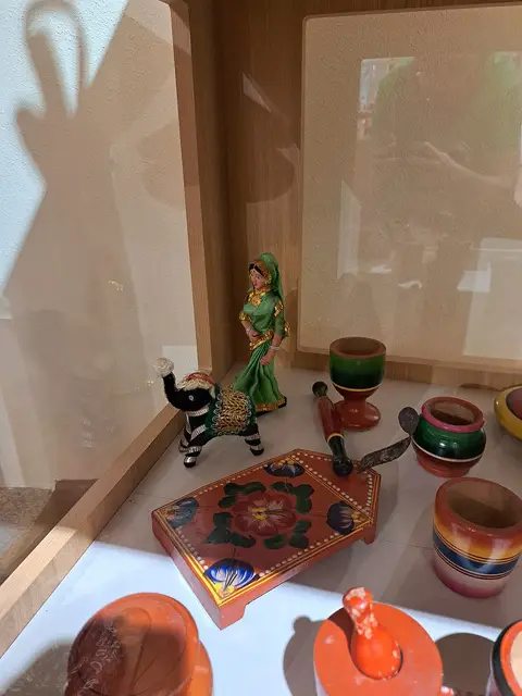 Vitrina de museu com brinquedos tradicionais indianos pintados à mão, incluindo figuras e peças de madeira