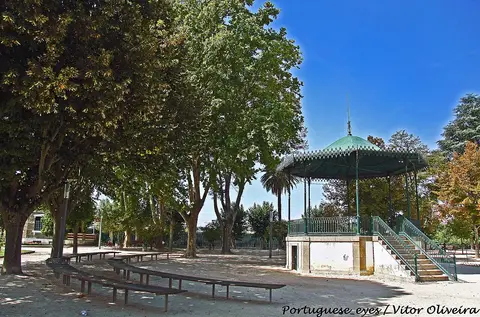 Coreto verde e bancos sob árvores no Jardim Público de Chaves