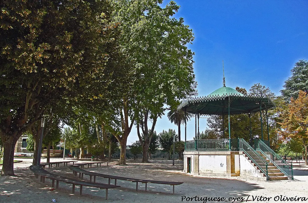 Coreto verde e bancos sob árvores no Jardim Público de Chaves