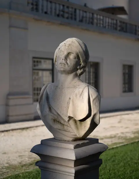 Busto de mármore sobre pedestal num jardim, com fachada de edifício clássico ao fundo