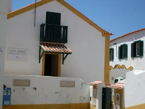 Fachada branca e amarela da Casa-Museu Afonso Lopes Vieira, com varanda verde e placa identificativa