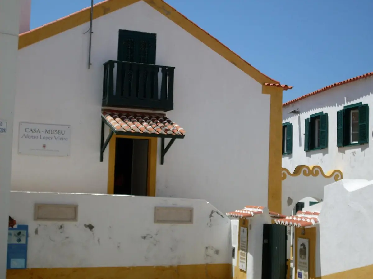 Fachada branca e amarela da Casa-Museu Afonso Lopes Vieira, com varanda verde e placa identificativa