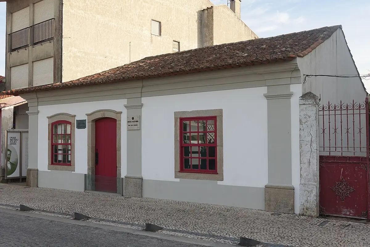 Fachada branca da casa museu Júlio Dinis, em Ovar, com porta e janelas de caixilharia vermelha