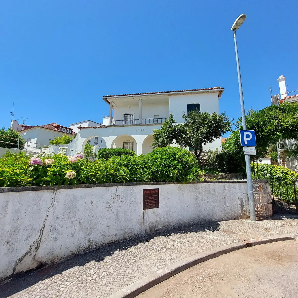 Casa-Museu Miguel Torga, edifício branco com varanda e arcadas, visto da rua com placa identificativa no muro