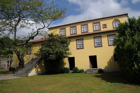 Fachada amarela da Casa-Museu de Camilo Castelo Branco, com escadaria de pedra e jardim relvado.