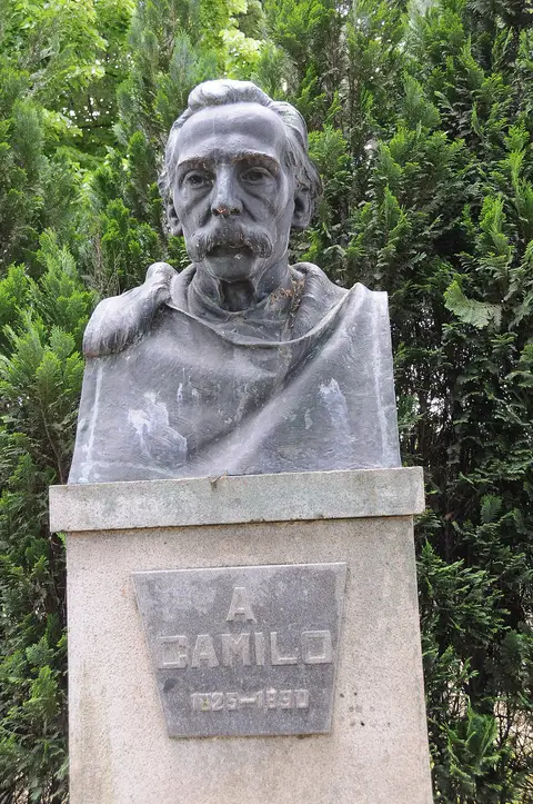 Busto de Camilo Castelo Branco sobre pedestal de pedra, rodeado de vegetação
